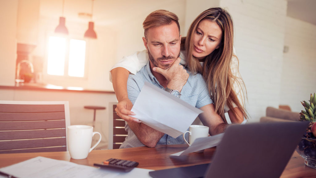 Couple français discutant de leur assurance auto devant leur véhicule familial