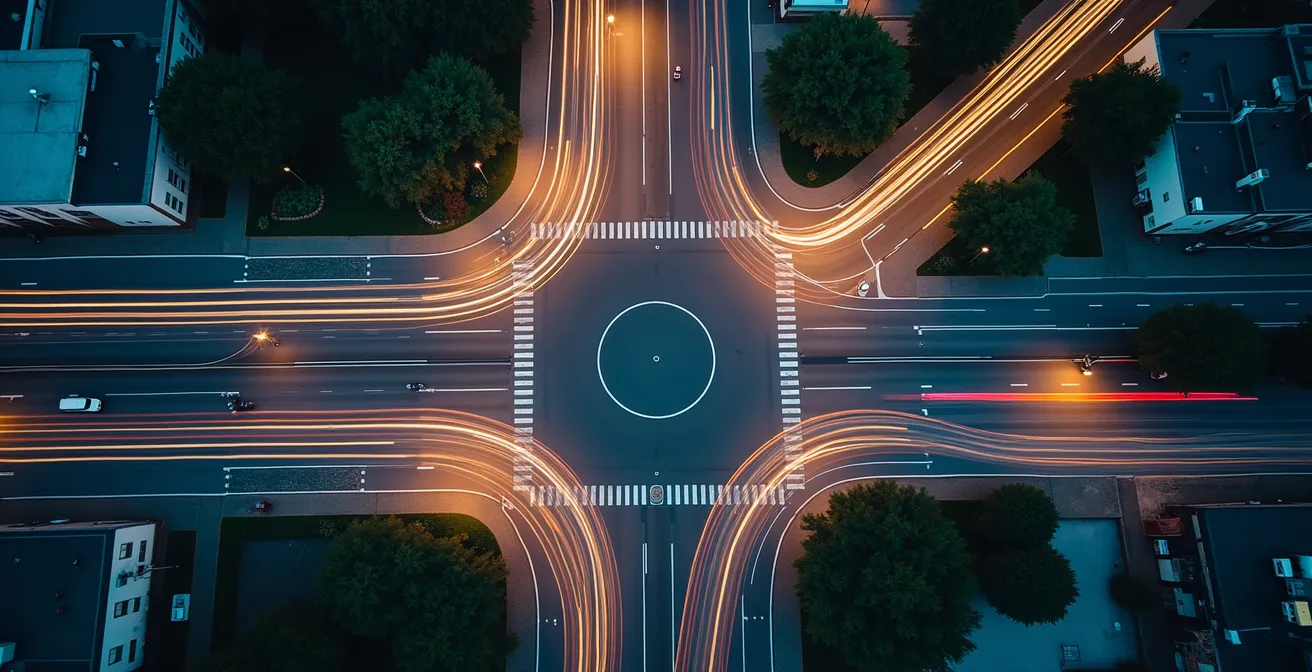Vue aérienne d'une intersection urbaine avec les trajectoires des véhicules matérialisées par des flux lumineux, illustrant la reconstruction d'un accident grâce aux données télématiques.